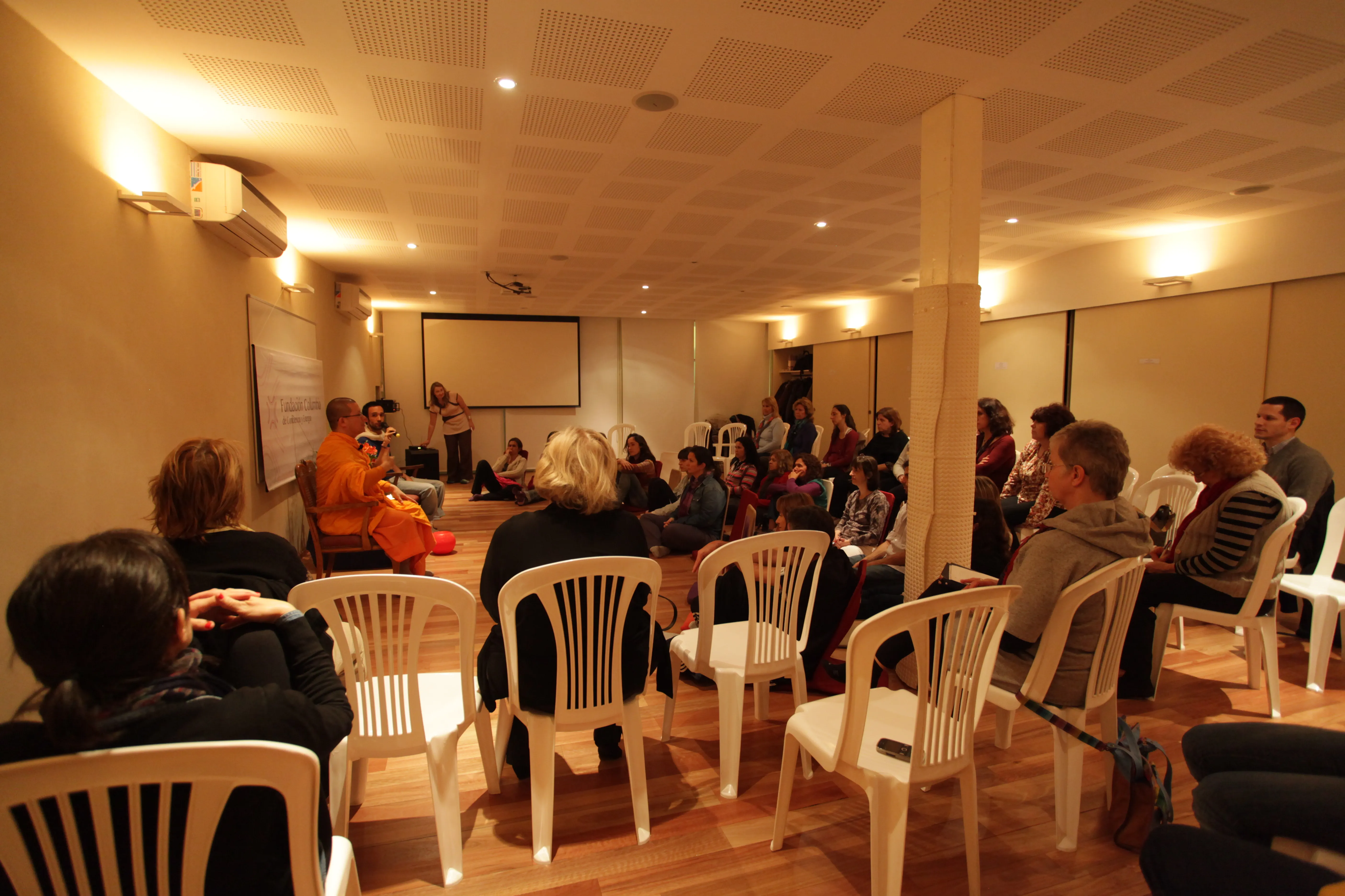 Participants on white plastic chairs listening to a monk at Fundación Columbia