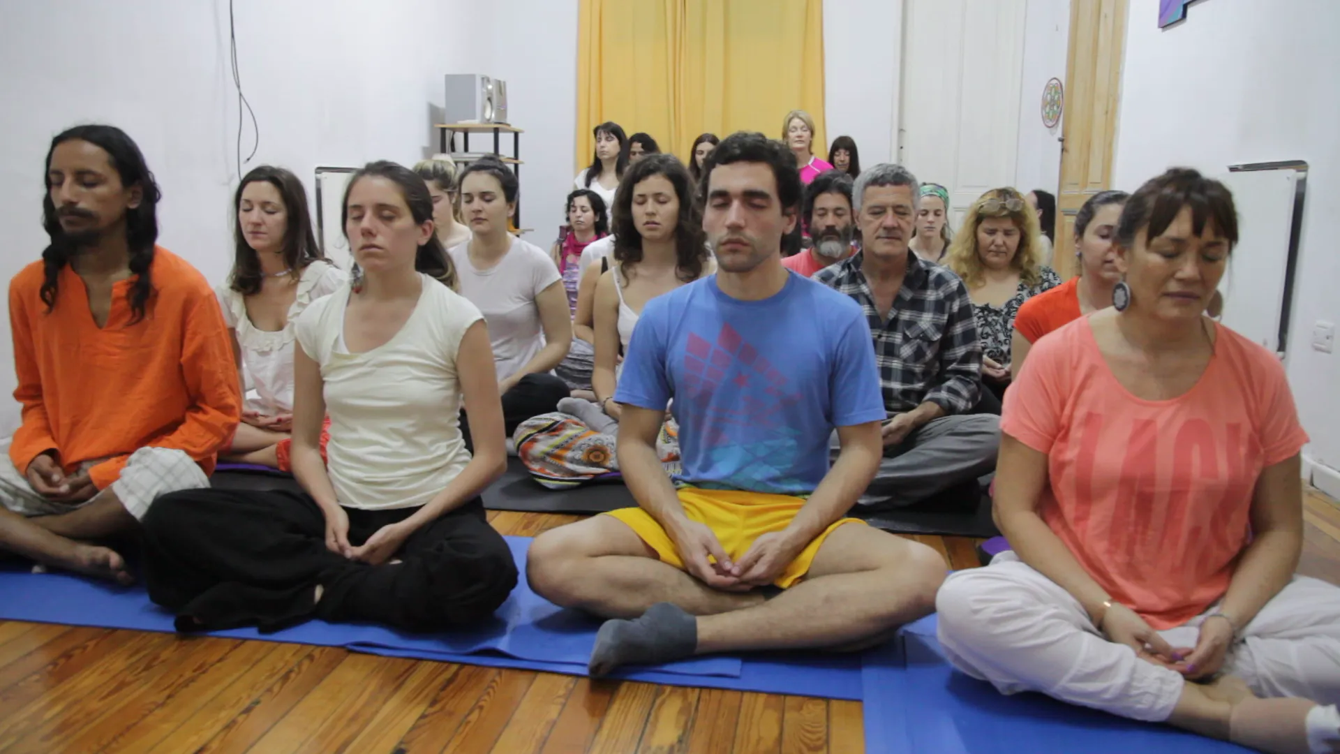 Participants sitting in meditation on blue mats at Desplegarte