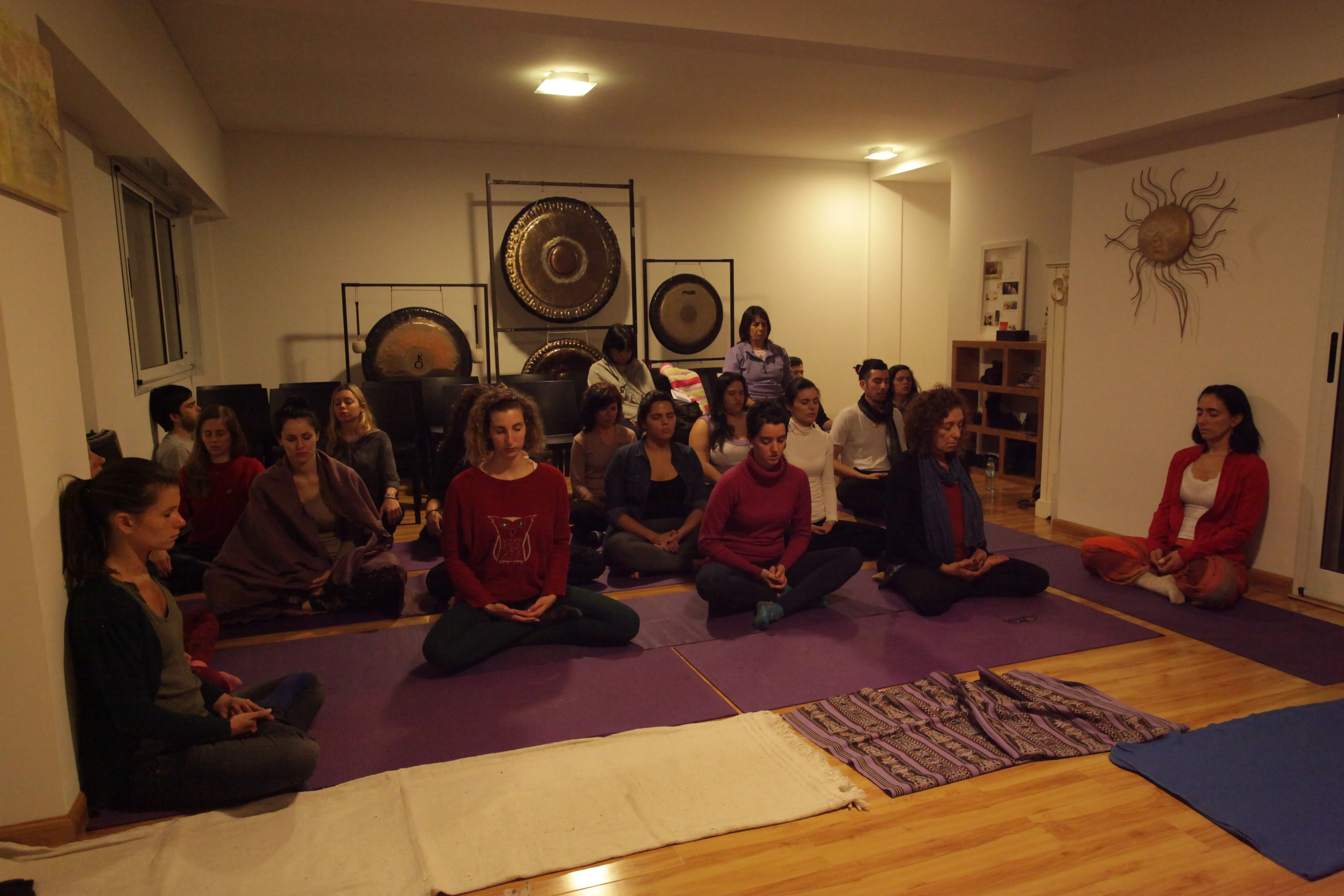 Participants sitting on mats around gongs at the Dharam studio