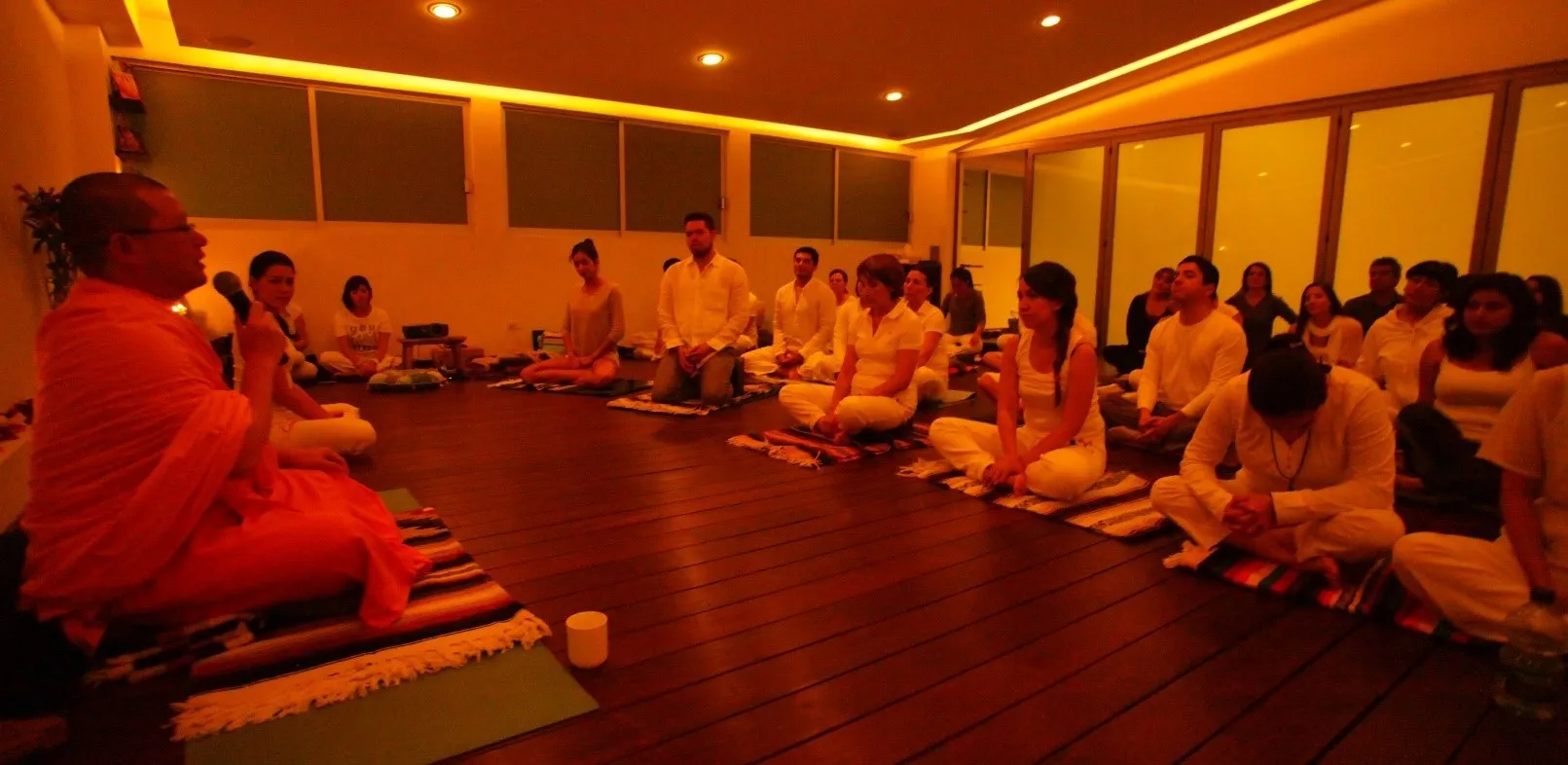 Teaching at the evening session at Ganesha Yoga, with participants in white seated on the floor