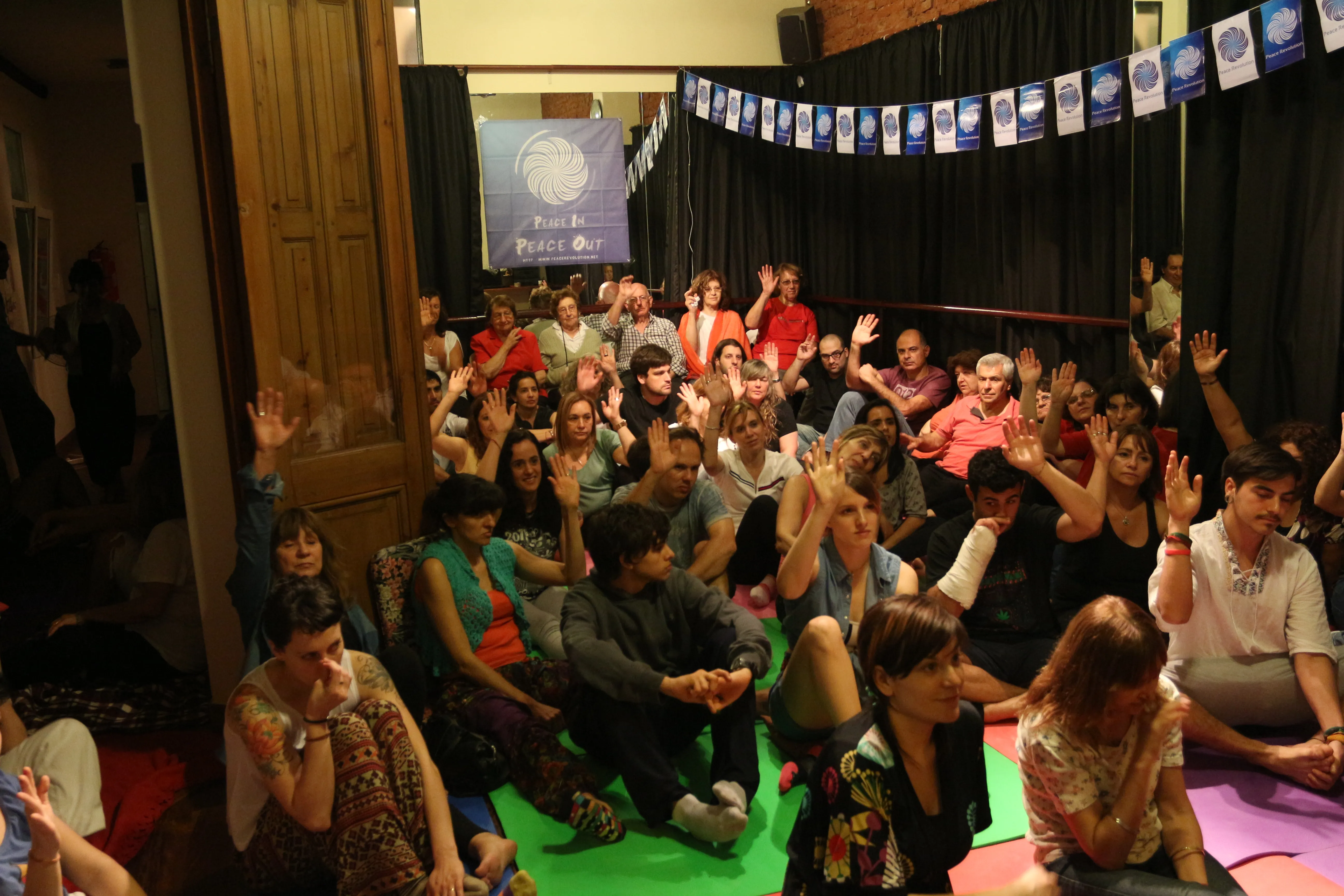 A packed hall at Jupapurá with many hands raised