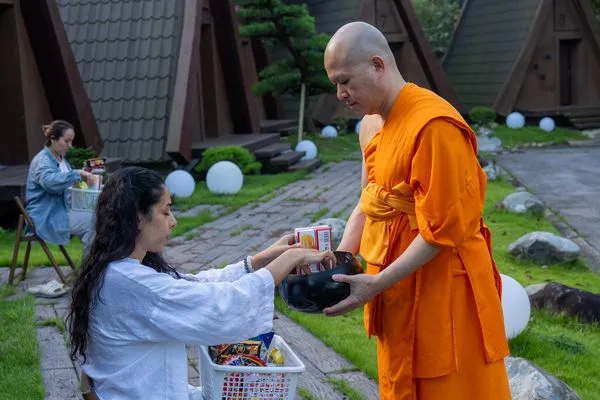 A participant offering food into a monk's bowl